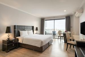 南芭堤雅Sirin Exclusive Hotel and Residence的酒店客房带一张床、一张桌子和椅子