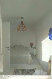 伊奥斯乔拉Cyclades, villa surplombant la mer的一间白色的卧室,配有床和玻璃门