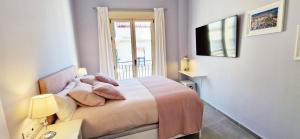马拉加Malaga Lodge Apartments的一间卧室配有一张带窗户的床和一台电视
