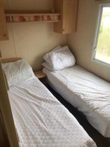 佩伦波斯6-8 berth caravan, Perran Sands Haven Holiday Park, Cornwall的小型客房 - 带2张床和窗户