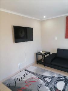 索韦托Serenity Guest House的客厅配有黑色沙发和地毯。