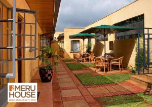 NkubuThe Meru House的房屋内带桌子和遮阳伞的庭院
