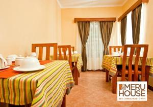 NkubuThe Meru House的酒店客房带两张床和一张桌子以及椅子。