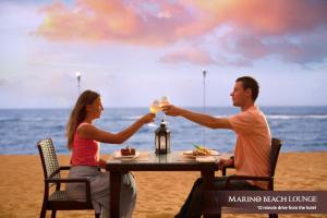 科伦坡科伦坡马里诺海滩酒店的男人和女人在沙滩上桌边喝葡萄酒