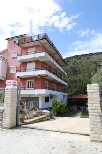 培拉特Villa Deart Berat的粉红色的建筑,前面有标志