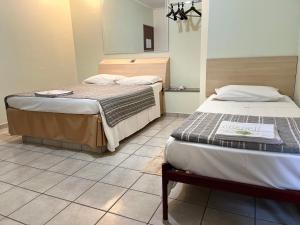 坎皮纳斯Hotel Taquaral的客房设有两张床,铺有瓷砖地板。