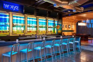 欧文拉斯科利纳斯雅乐轩酒店的酒吧,酒吧内有蓝色凳子,房间有酒精饮料