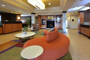 威斯维尔维斯维尔费尔菲尔德客栈及套房酒店的酒店大堂设有橙色的沙发和桌子。
