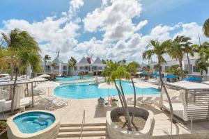棕榈滩Courtyard by Marriott Aruba Resort的度假村的游泳池,种植了棕榈树,配有椅子
