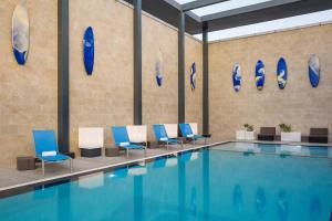 阿可贺巴雅乐轩达兰酒店的墙上设有蓝色和白色椅子的游泳池