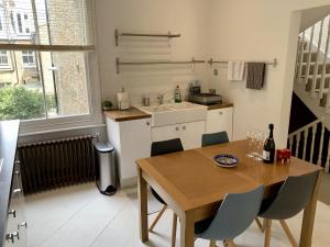伦敦Lovely newly refurbished apartment in Battersea的厨房配有木桌、椅子和水槽