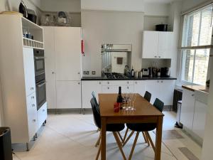 伦敦Lovely newly refurbished apartment in Battersea的厨房配有白色橱柜和木桌