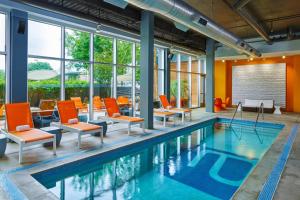 休斯顿休斯敦画廊雅乐轩酒店的一座室内游泳池,旁边设有橙色椅子和椅子