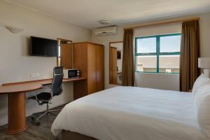 贝尔维尔开普敦泰格谷万豪Protea酒店的配有一张床、一张书桌和一扇窗户的酒店客房
