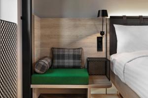 里尔Moxy Lille City的一间卧室配有一张床和一个绿色长凳