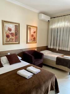 阿帕雷西达Pousada Estrela Guia的酒店客房,配有两张床和椅子