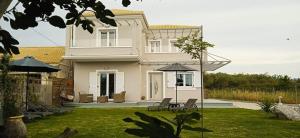 罗达Spiridoula Luxury Villa的一座带椅子和遮阳伞的大型白色房屋