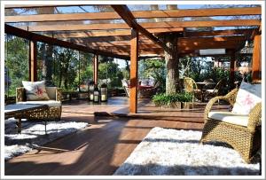 格拉玛多Pousada do Verde Gramado的庭院设有藤椅和木制凉亭。