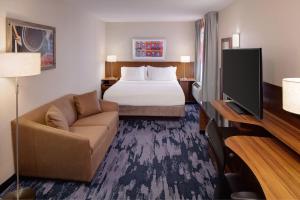 纽约纽约曼哈顿/市中心东费尔菲尔德套房酒店的酒店客房配有床、沙发和电视。