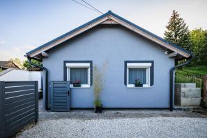 巴拉顿凯奈谢Orchidea Apartman的蓝色的房子,设有两扇窗户和围栏