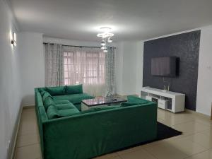 内罗毕Nersheys 2 bedroom Apartment near Junction Mall的客厅配有绿色沙发和电视