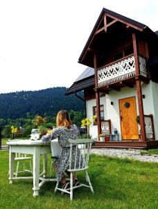 克罗奇琴科Gazdówka - najlepsza miejscówka domek w Pieninach的坐在房子前面桌子上的女人