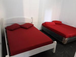 伯迪亚哥Hostel Canto de Bertioga的客房内的两张床和红色床单