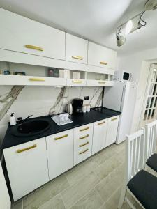 锡比乌Luxor Apartament Sibiu的厨房配有白色橱柜和黑色台面