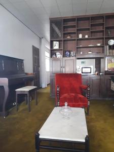 库里提巴Quartos em Casa próximo ao Parque Bacacheri的客厅配有红色椅子和钢琴