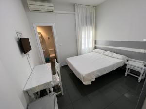 巴萨Hostal Venta Del Sol的白色的小房间,配有床和桌子