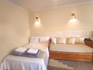 戈亚斯州上帕莱索Chalé com ar condicionado e garagem的一间设有两张床的房间和墙上的两盏灯
