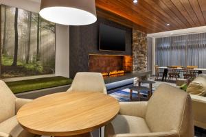 阿尔科Fairfield by Marriott Inn & Suites Knoxville Airport Alcoa的客厅设有壁炉、桌子和椅子
