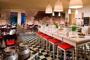 弗赖辛万豪酒店慕尼黑机场店的餐厅设有长长的酒吧,配有红色椅子
