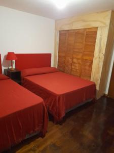 图蓬加托火山Mirador de Estrellas的一间卧室配有两张床和红色的床罩