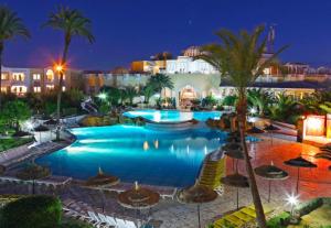 米多恩杰尔巴假日海滩酒店的棕榈树和建筑的夜间游泳池