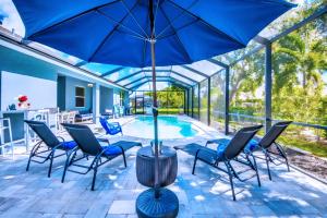 珊瑚角Beautiful Cape Coral Oasis! King Bed, BBQ, Heated Pool, PVT Yard & Much More!的一个带椅子和遮阳伞的庭院和一个游泳池