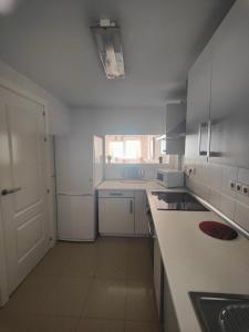加鲁查Apartamento Playa del Faro的白色的厨房设有水槽和台面