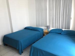 普拉亚斯Flor de Lis Beach House, villa vacacional的配有蓝色床单的客房内的两张床