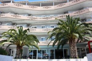 尼亚·卡利克拉提亚卡利亚蒂斯酒店的两棵棕榈树,在一座建筑前