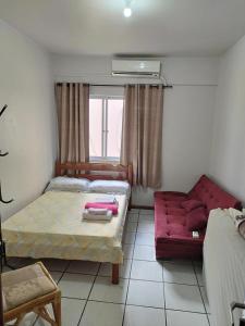 伊塔佩马APT Praia Central Itapema 90MTS do Mar的一间卧室配有一张床和一张红色的沙发