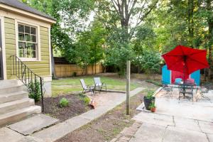 孟菲斯J Birds' Cottage Midtown Memphis的一个带桌子和红色遮阳伞的庭院