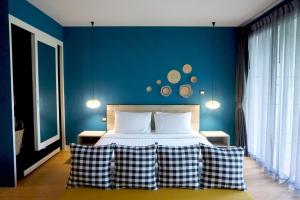 查龙Signature Phuket Resort SHA Plus的一间卧室配有一张蓝色墙壁的床