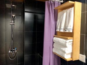 呼和浩特呼和浩特青檬国际青年旅舍的一间带紫色淋浴帘的淋浴的浴室