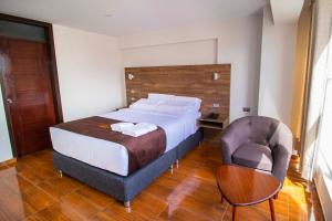 阿雷基帕Hotel Cumbre Real Airport - Arequipa的一间卧室配有一张大床和一把椅子