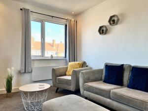 唐克斯特Lovely Serviced Apartment - Near Doncaster Hospital的客厅配有两把椅子、一张沙发和一张桌子