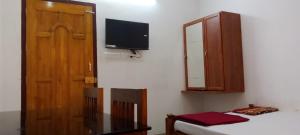特里凡得琅Somatheertham Ayurvedic Resort的一间设有床铺、橱柜和电视的房间