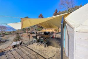 富士河口湖Retreat Camp Mahoroba的遮阳篷,在甲板上,配有桌椅