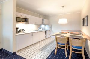 青斯特Aparthotel Zingst的厨房配有白色橱柜和桌椅