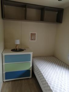 RocbaronMobilhome的一间卧室配有一张床和一个带灯的梳妆台