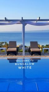 佩科霍里Bungalow White Tennis Apartments & Suites的一个带两把躺椅的游泳池,欢迎您在白色标志下
